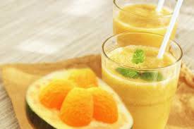 um copo de suco de pequi com um pequi cortado ao meio